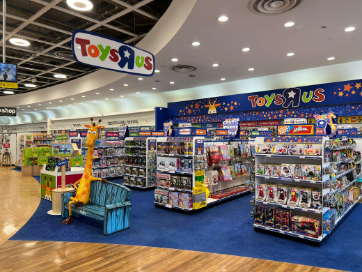 ToysRus store with model giraffe figurine on a bench.